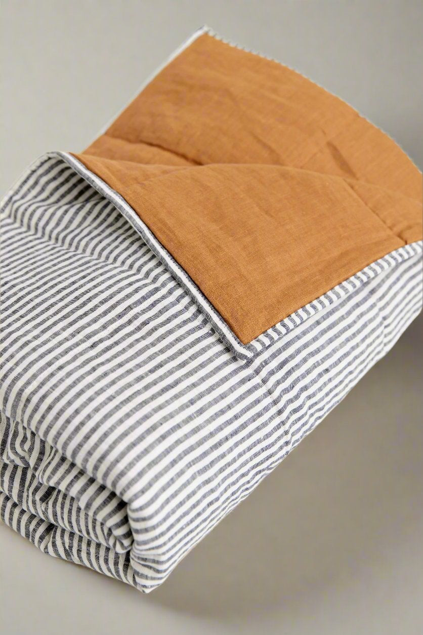 Elegant linen bedding set styled in a minimal, modern bedroom with warm lighting. King size Linen Quilted Blanket #color_burnt-orange-stripe